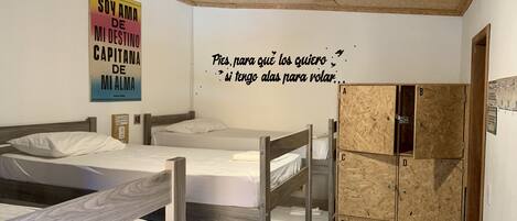 Una habitació de dormitori amb llits superposats, un sostre de fusta i una paret amb cites motivacionals.