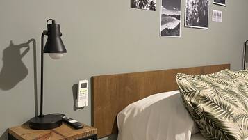 Quarto com cama, mesa de cabeceira com abajur, relógio de parede e várias fotos emolduradas.
