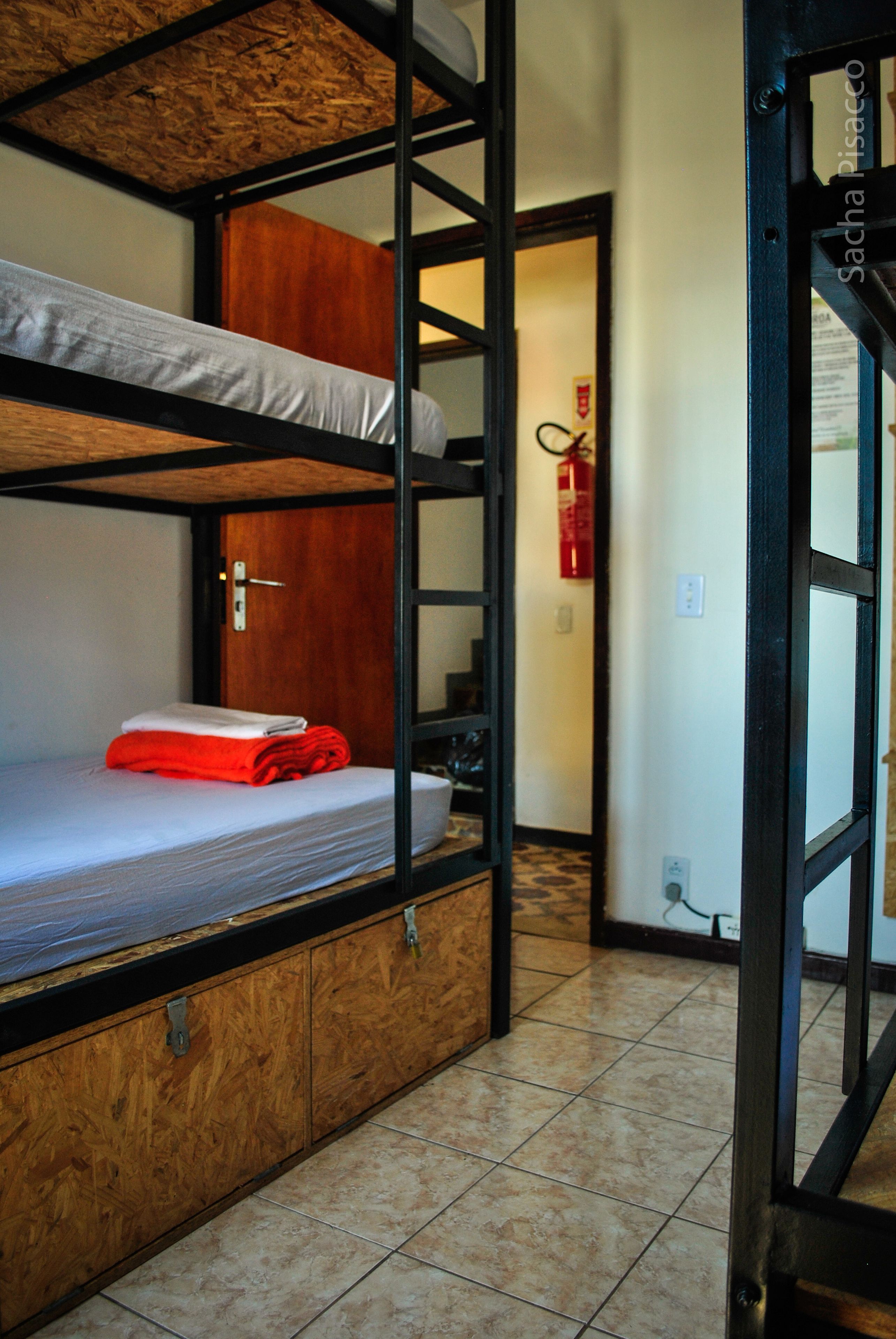 Habitación con literas, una puerta de madera y un extintor en la pared.