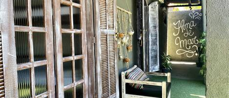 Un intérieur chaleureux avec un banc en bois, un mur orné d’objets décoratifs suspendus et une enseigne indiquant « Alma de Maio ».