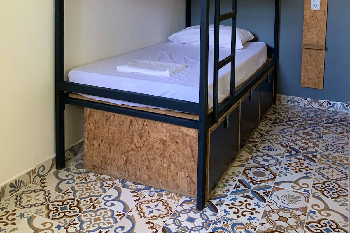 A bunk bed room with a wooden floor and patterned tiles.