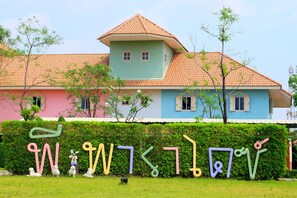 A colorful house with a green roof and a pink and blue facade.