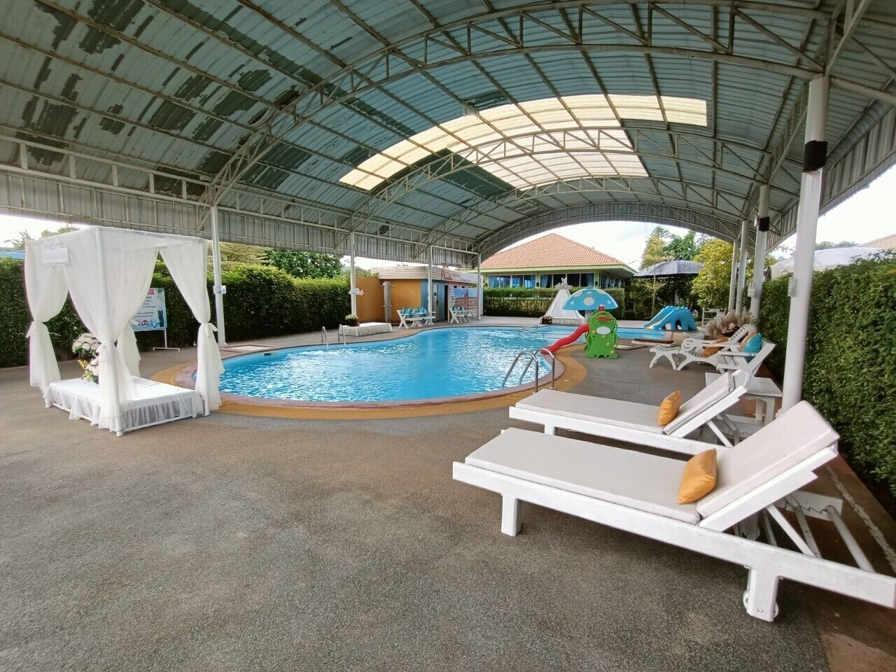 A covered pool area with lounge chairs, a small pool, and a children's play area.
