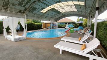 A covered pool area with lounge chairs, a small pool, and a children's play area.