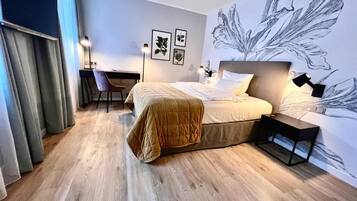 Ein modernes Hotelzimmer mit Bett, Schreibtisch, Stuhl, einer großen Wandmalerei und Holzboden.
