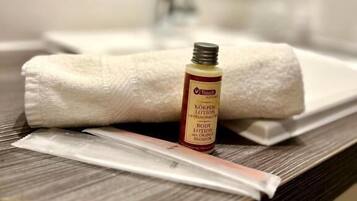 A bathroom with a towel, a bottle of lotion, and a razor on a counter.