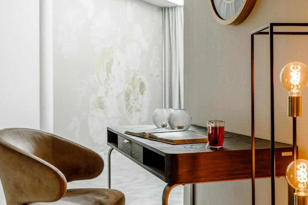Una habitación moderna con un escritorio de madera, una silla de cuero y un aplique de pared.