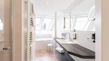 Ein modernes Badezimmer mit Dachfenster, einer Badewanne, einem Waschtisch mit Spiegel und einem Handtuchhalter.