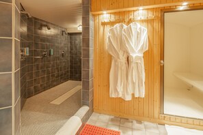 A bathroom with a shower, a bathtub, and a wooden wall. - Hotel Ambiente (Bueckeburg)
