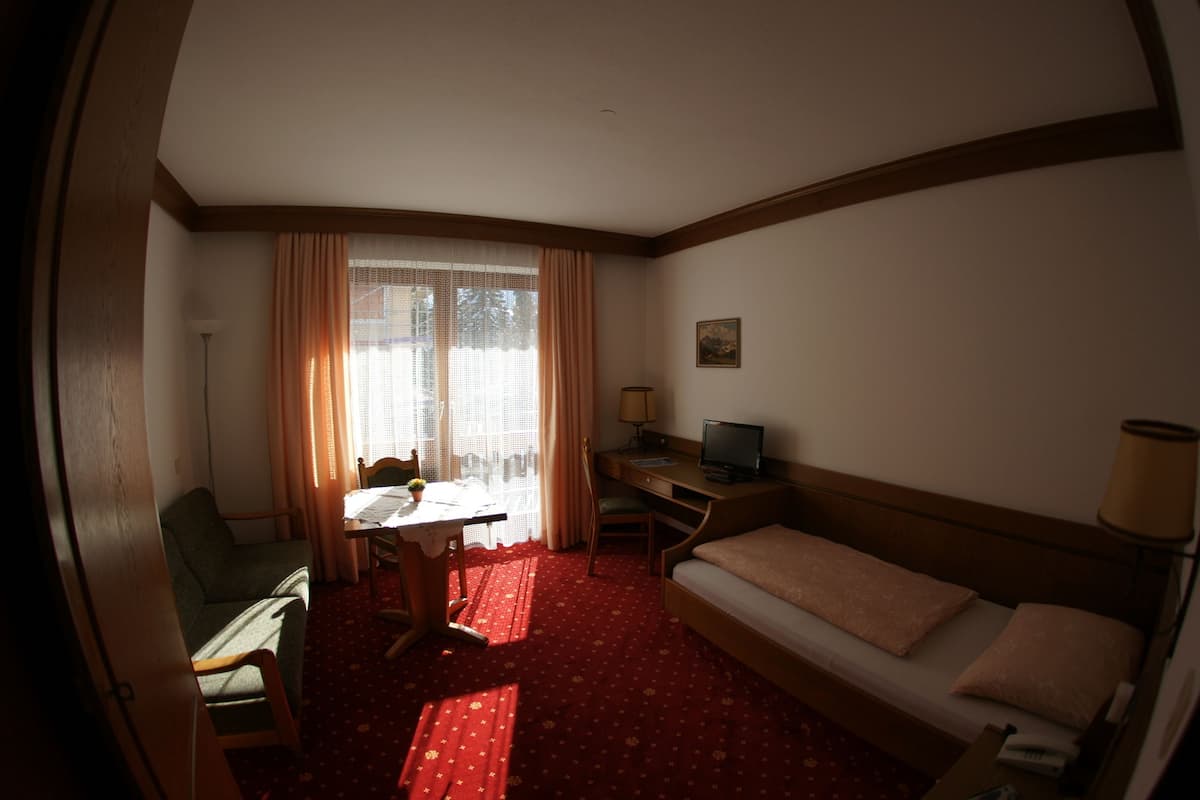 Une chambre d’hôtel de taille réduite, comprenant un lit, un bureau, une chaise et une petite table.