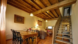 Ein Essbereich mit Holztisch und Stühlen, einem Fernseher und einer Treppe.