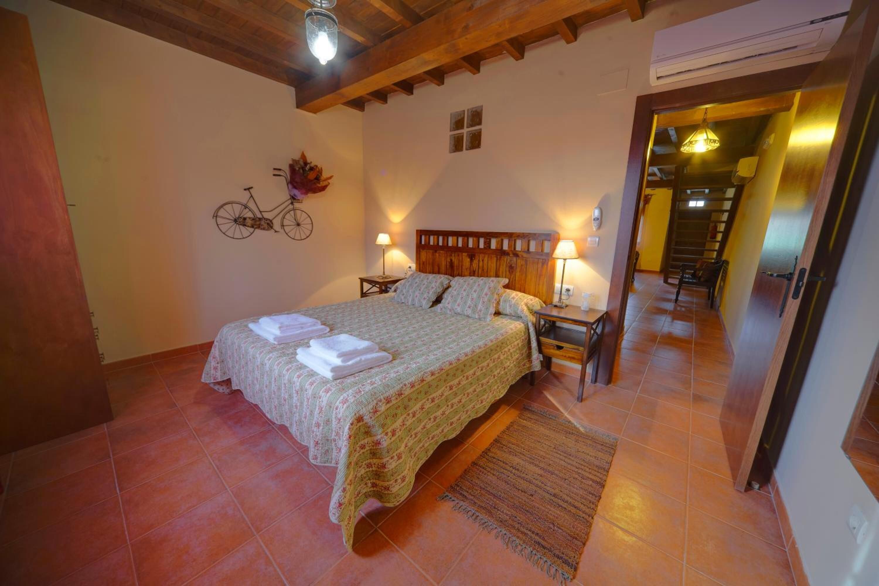 Une chambre à coucher comprenant un lit, deux tables de chevet, une décoration murale représentant un vélo et un escalier menant à une autre pièce.