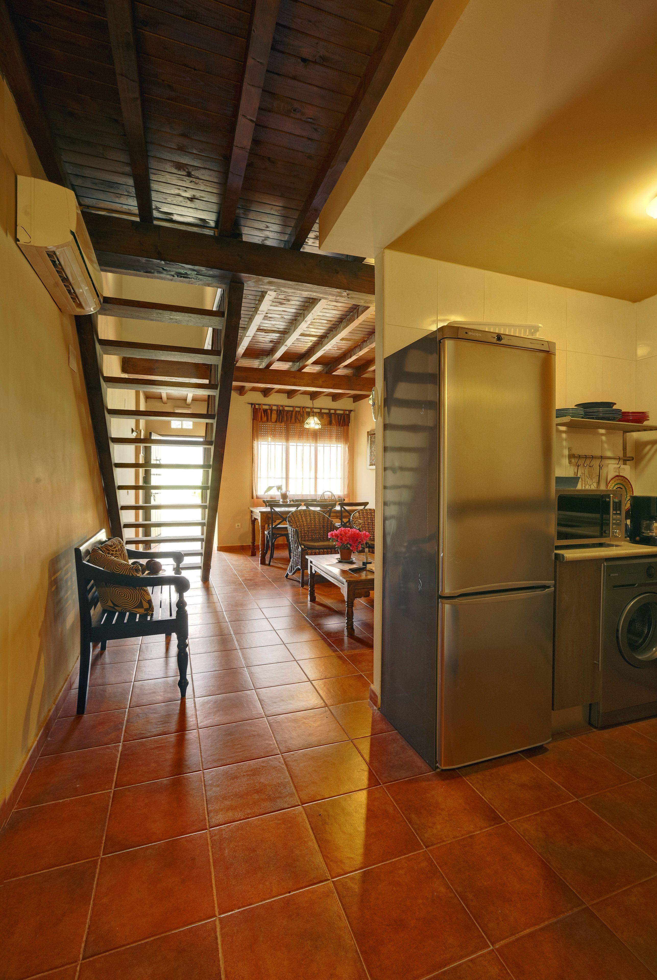 A kitchen with a stainless steel refrigerator, a washing machine, and a dining area with a table and chairs.