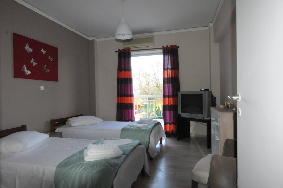 Habitación de hotel con dos camas, televisión y escritorio.