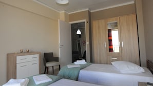 A hotel room with two beds, a desk, a chair, and a wardrobe. - Kinetta Apartments (Oropos)