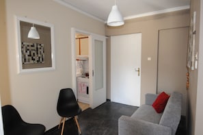 A modern living room with a grey sofa, a black chair, and a white pendant light.