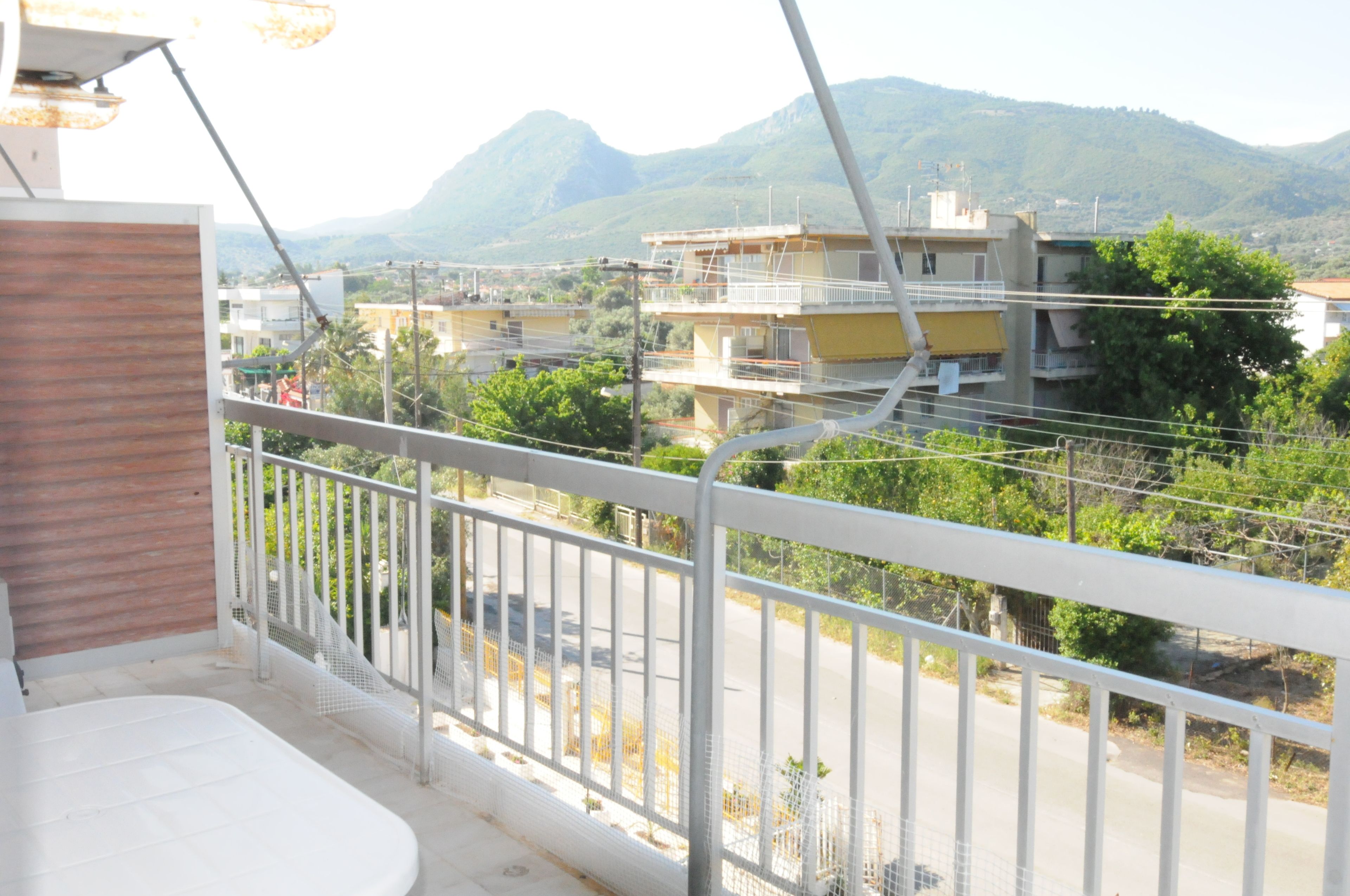 A balcony with a view of a residential area, including houses and a mountain in the background.