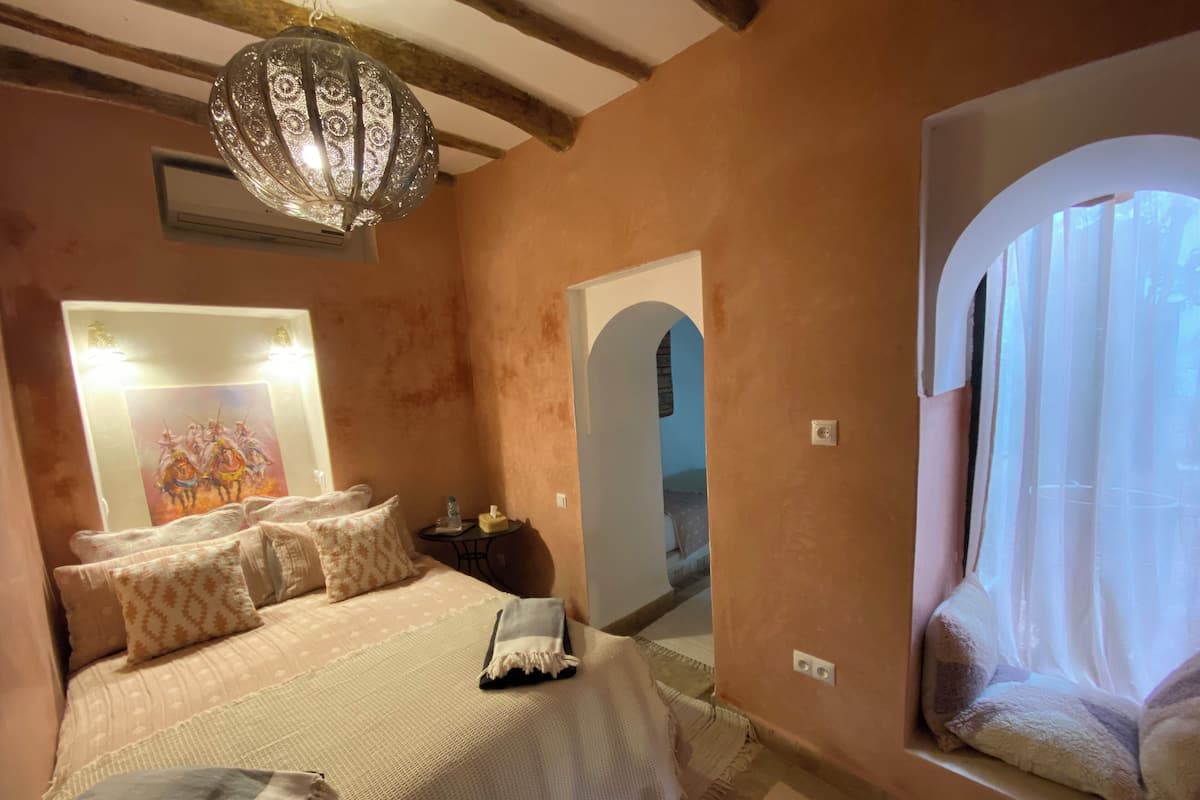 Un dormitorio con una cama grande, un espejo, una araña de cristal y una ventana con cortinas.