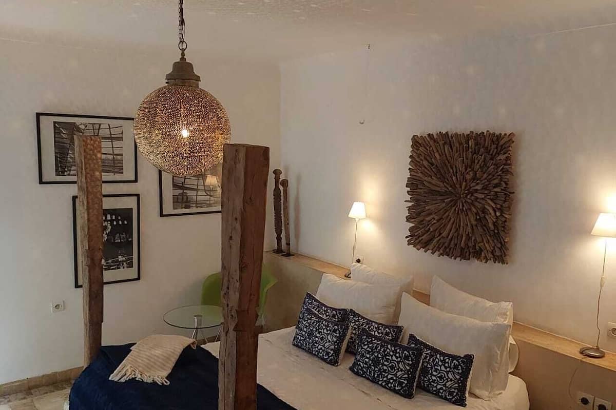 Un dormitorio con cama, lámparas de noche, una obra de arte en la pared y una lámpara colgante.