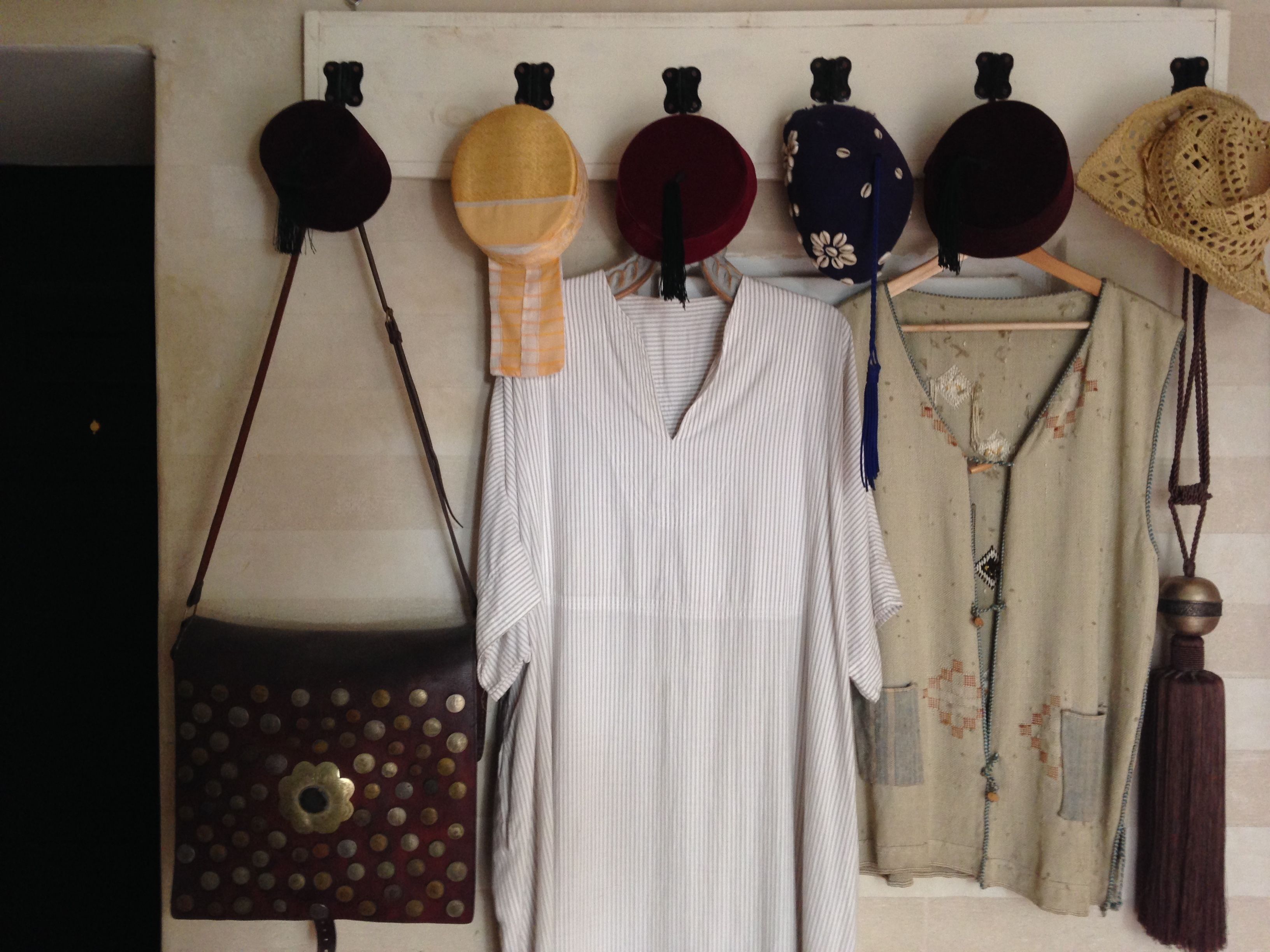 A wall displaying various hats and a striped dress.