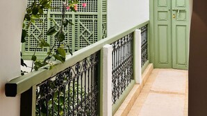 A view through an archway of a building with a green door and a tiled roof. - Riad Timila (Marrakech)