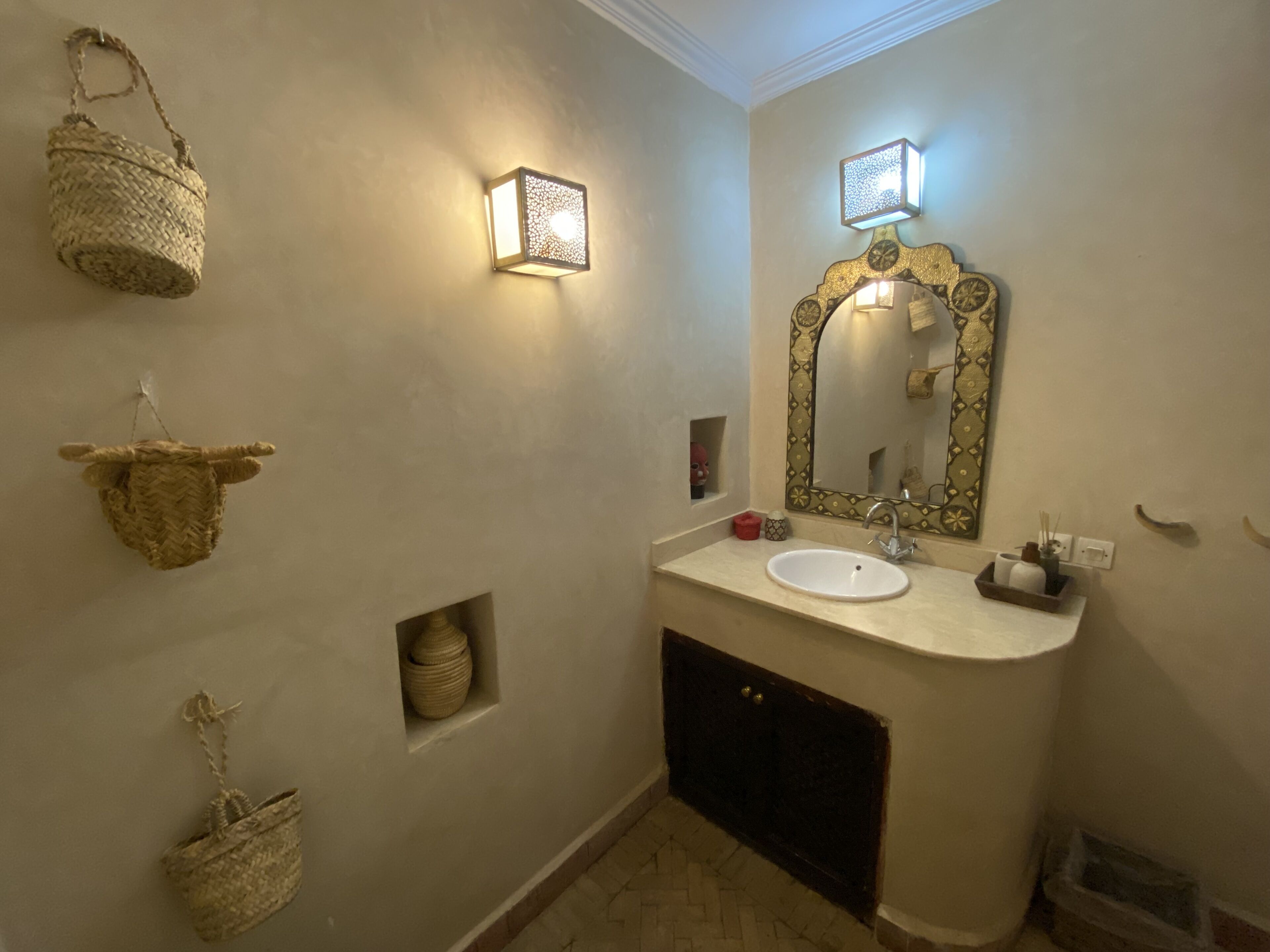 Une salle de bain équipée d’un lavabo, d’un miroir et d’appliques murales.