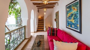 A corridor with a red sofa, wooden beams, and a star-shaped light fixture. - Riad Timila (Marrakech)