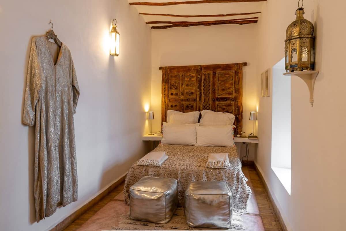 Un dormitorio con cama, dos mesitas de noche, un perchero y un farol decorativo.