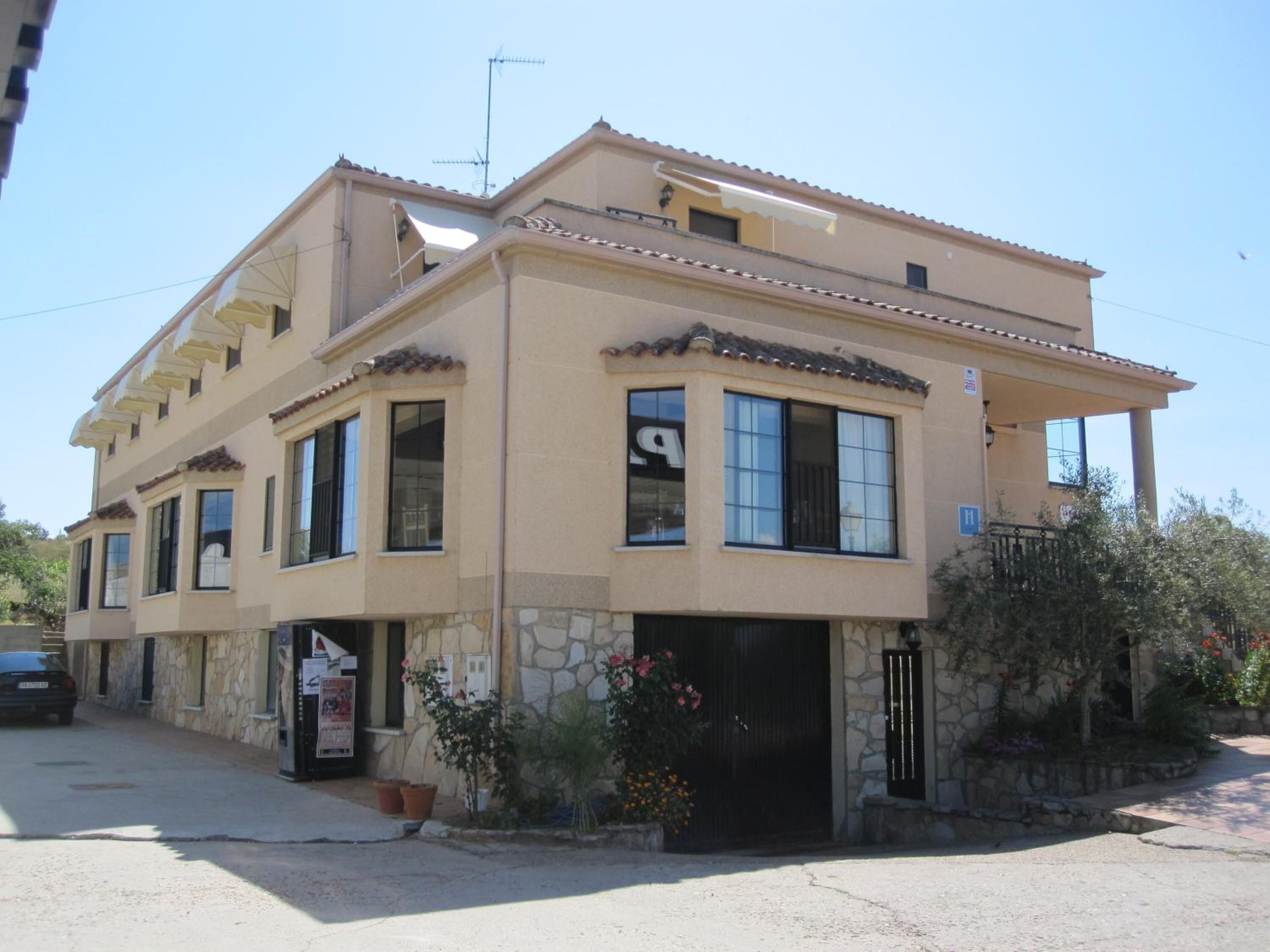 A two-story building with a stone facade, multiple windows, and a visible entrance with a door.