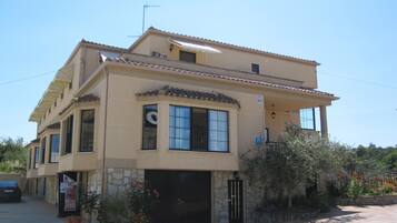 A two-story building with a stone facade, a black garage door, and a small balcony.