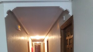 Un pasillo estrecho y bien iluminado con suelo de baldosas y una puerta de madera a la derecha.