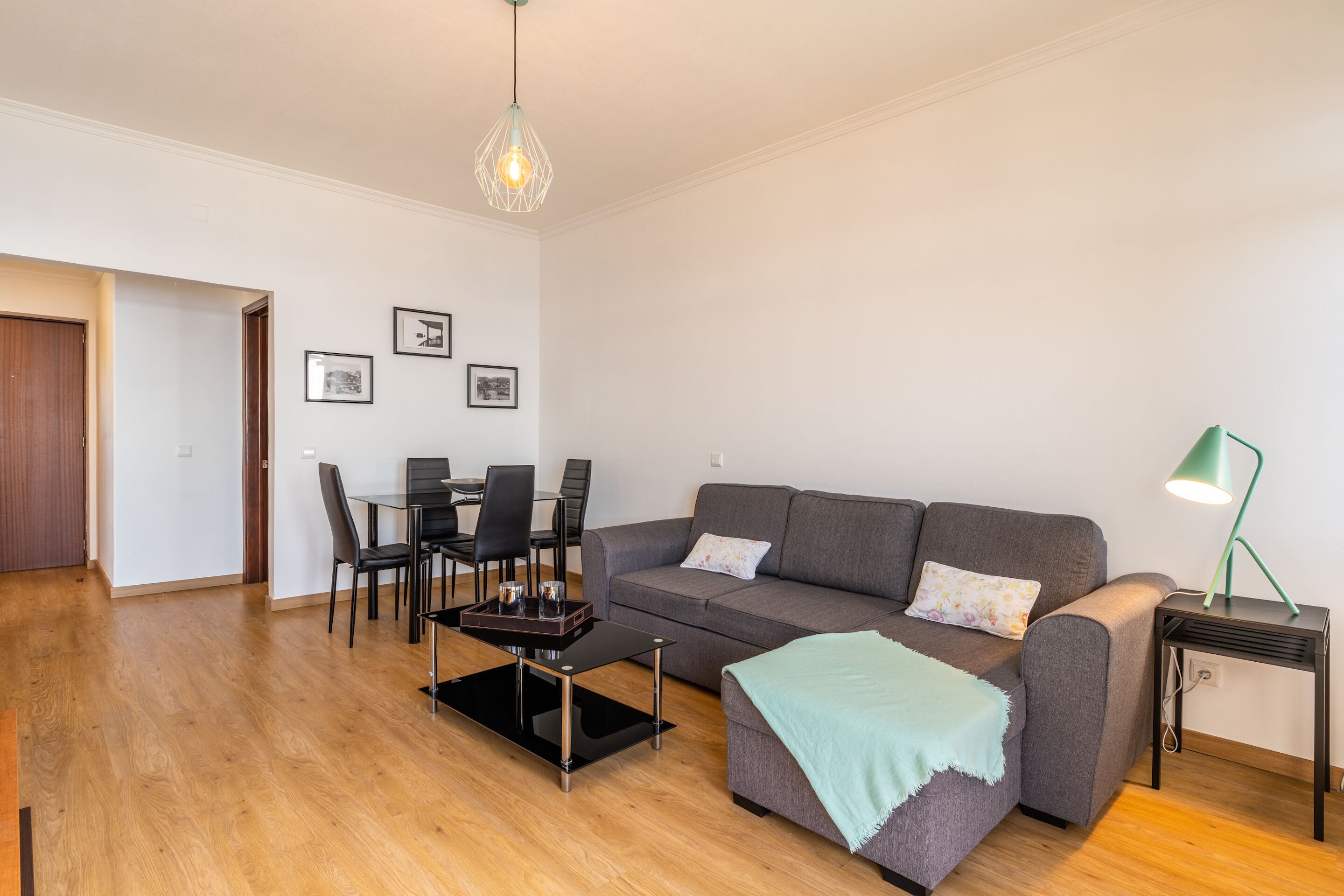 A modern living room with a sofa, coffee table, and dining area.