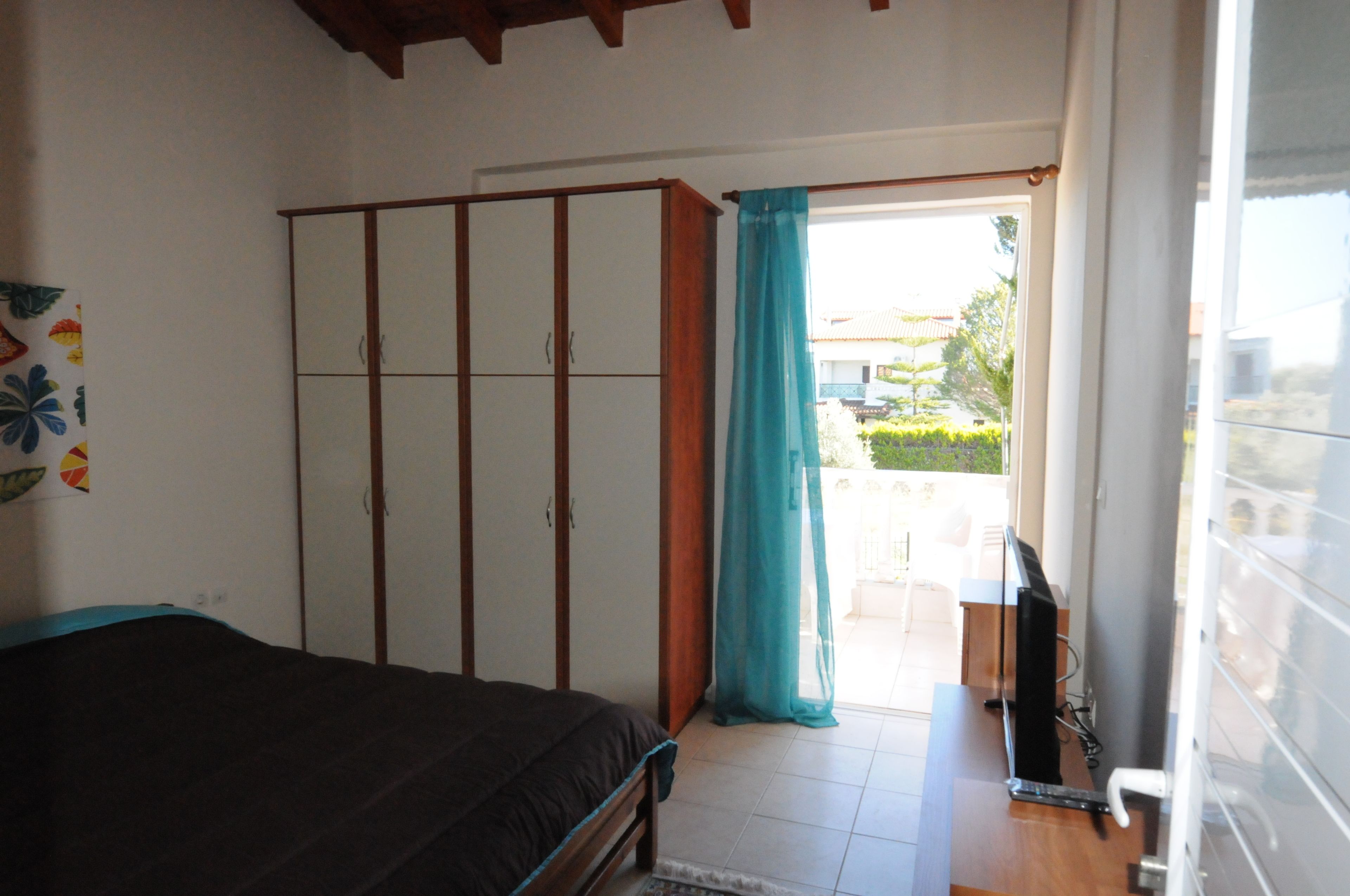 Ein Schlafzimmer mit Bett, Kleiderschrank und Fernseher.