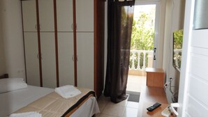Une chambre d’hôtel comprenant un lit, une armoire, un balcon avec vue et un bureau avec une télécommande.