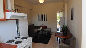 Une cuisine compacte équipée d’une cuisinière, un coin repas avec une table et des chaises, et un salon avec un canapé.