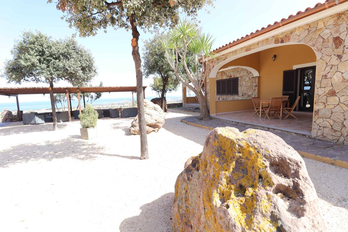 A stone building with a patio, outdoor seating, and a view of the sea.