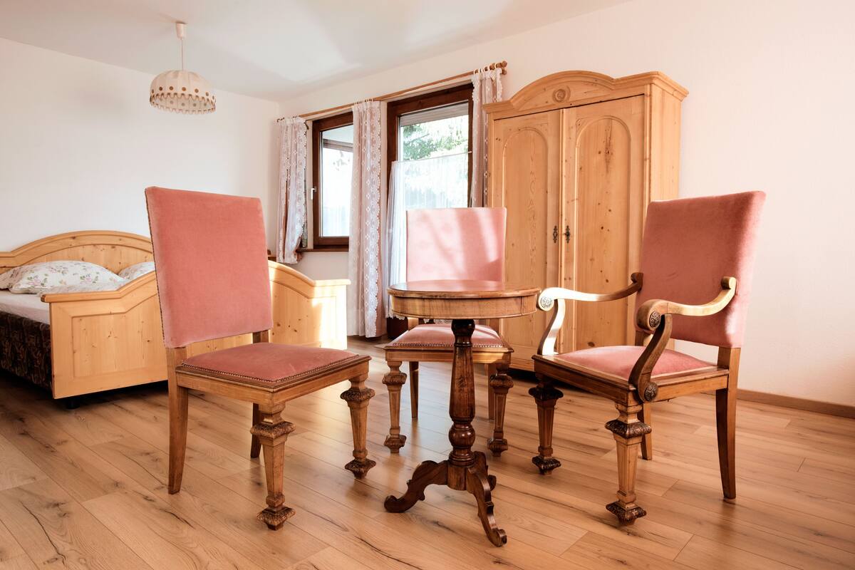 Ein Zimmer mit einem hölzernen Bett, zwei Holzstühlen mit gepolsterten Sitzen, einem Holztisch und einem Holzschrank.