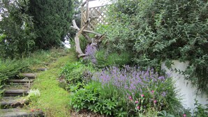 A garden with a wooden trellis, various plants, and a white wall. - Haus Fink (Innsbruck)