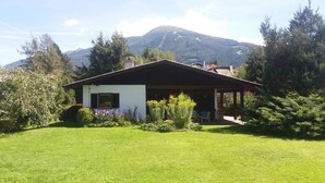 A house with a sloped roof, surrounded by a well-maintained lawn and flowering plants. - Haus Fink (Innsbruck)