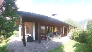 A covered patio with stone flooring, outdoor furniture, and a view of the surrounding landscape. - Haus Fink (Innsbruck)