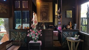 Una habitación acogedora con un escritorio de madera, un florero y un gran ventanal con persianas.