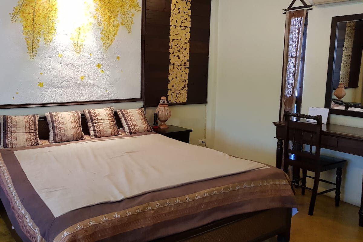 Ein Hotelzimmer mit einem großen Bett, einem Schreibtisch und einem Sessel. An der Wand hängt ein dekoratives Bild und ein Spiegel.