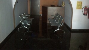 A reception area with a reception desk, a fire extinguisher, and a waiting area with chairs. - Ruby Kay Hotel (Accra)