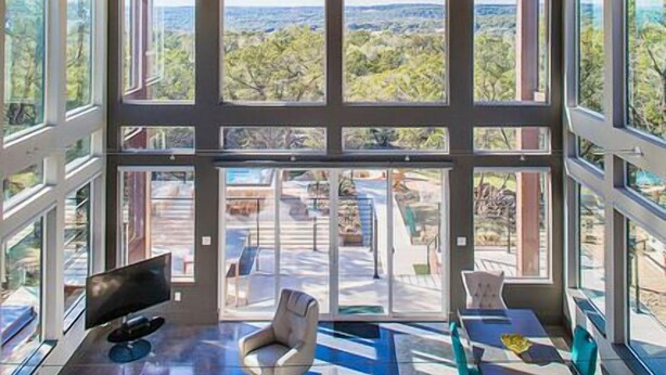 Un amplio salón con techo alto, ventanas grandes y vistas al exterior.