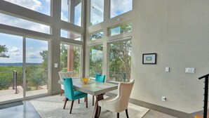 Un comedor con una mesa grande, sillas y vistas amplias a través de grandes ventanales.