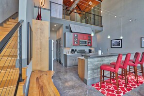 A modern kitchen with grey cabinets, a red island, and a red bar stool area. - Romantic Hill Country Luxury - Perfect getaway for two! (Wimberley)