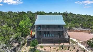 A two-story building with a blue roof, surrounded by a landscaped garden with various plants and a paved walkway.