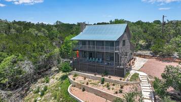 A two-story building with a balcony, surrounded by a landscaped garden and dense forest.