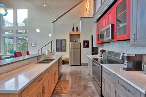 A modern kitchen with a large island, stainless steel appliances, and red cabinetry. - Romantic Hill Country Luxury - Perfect getaway for two! (Wimberley)
