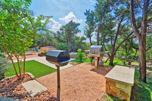Ein Garten mit Grill, Steinpflanzgefäß und gepflegtem Rasen.